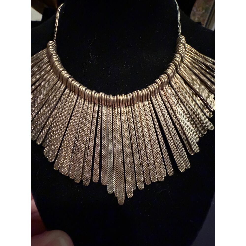 Fringe Necklace in a gold tone. statement piece has a fringed graduated, bars